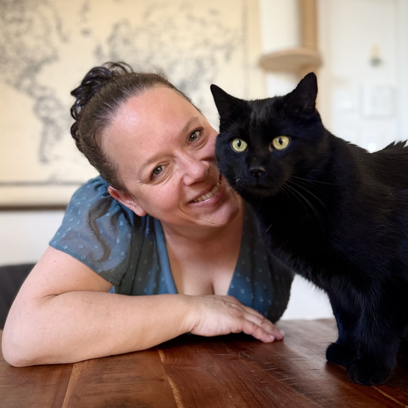 Sieglinde Loibichler stützt sich an einem Holztisch auf, neben ihr sitzt ihre schwarze Katze